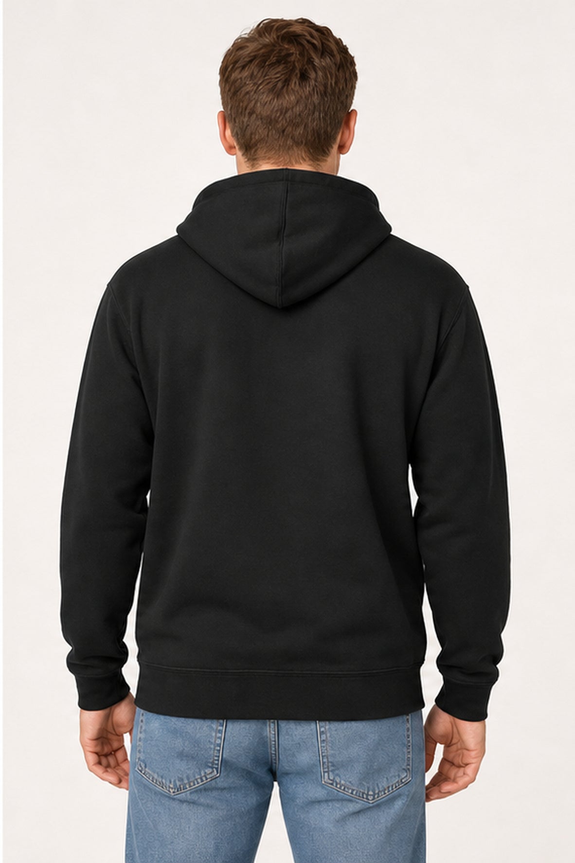 A man viewed from the back wearing a plain black pullover hoodie and blue jeans against a light gray studio background.