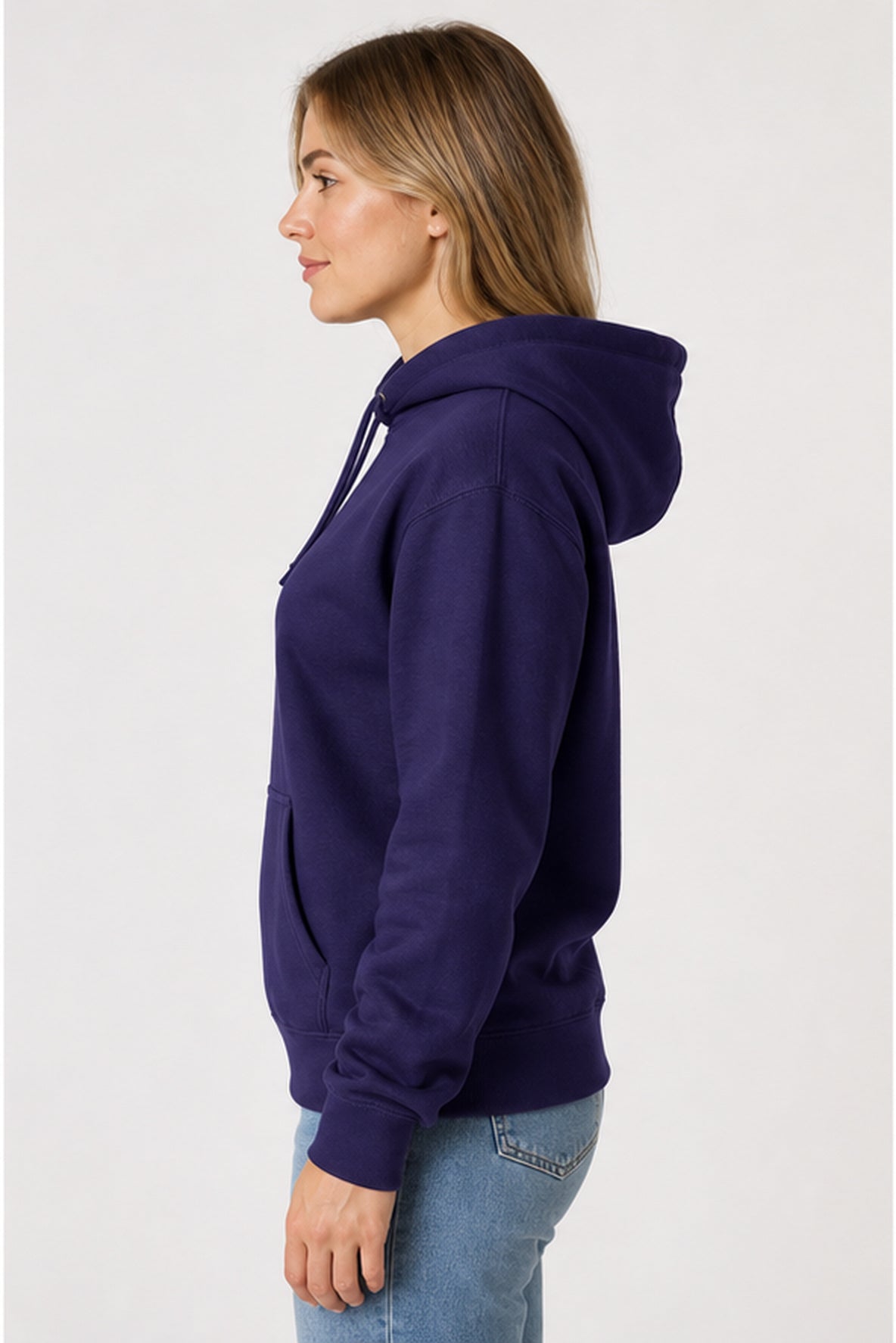 A woman shown in profile wearing a dark purple pullover hoodie and light blue jeans against a plain light gray studio background.